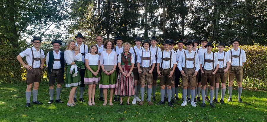 Großes Gruppenfoto auf einer Wiese: Plattler in Lederhosen und Frauen im Dirndl