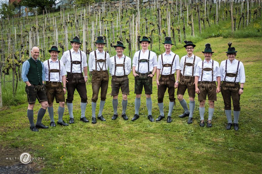 Gruppenfoto in Tracht mit Hut vor einem Weingarten