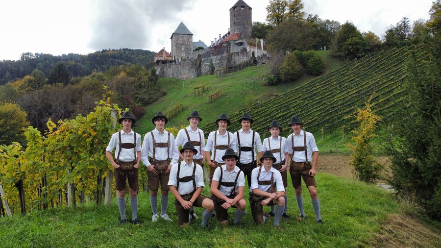Gruppenfoto in Tracht in einem Weingarten, im Hintergrund eine Burg